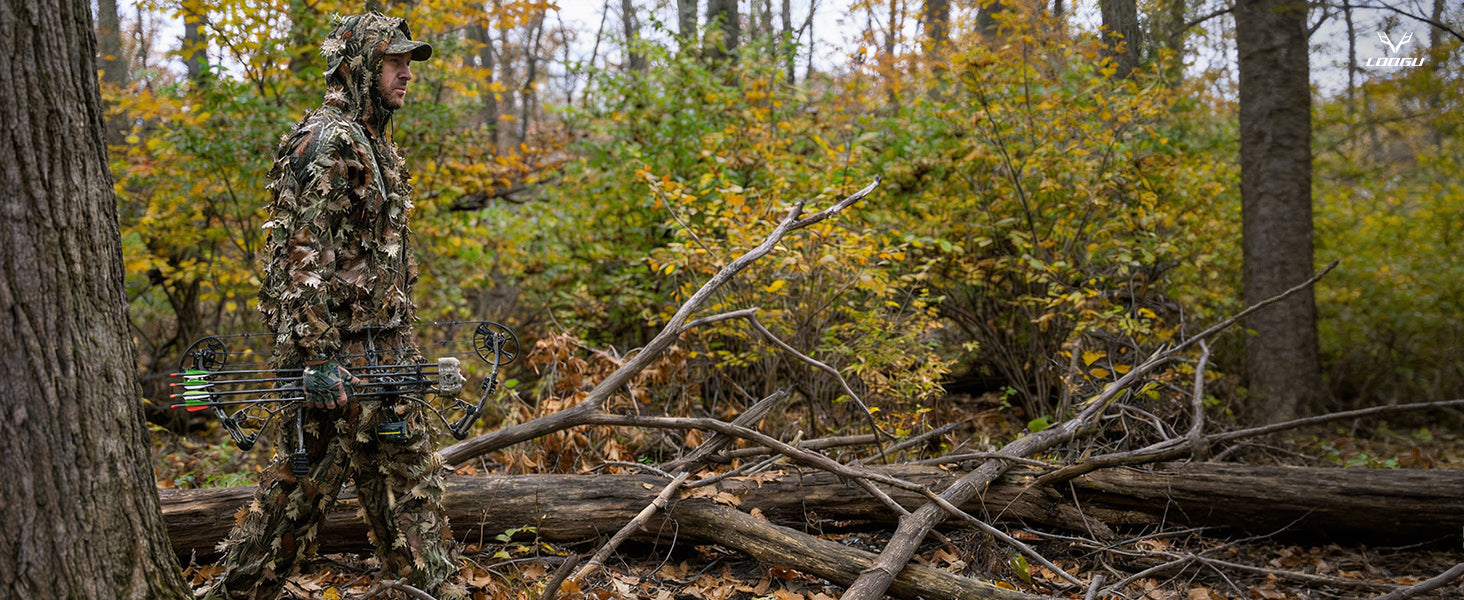 Hunter wearing leafy camouflage in mixed woodland